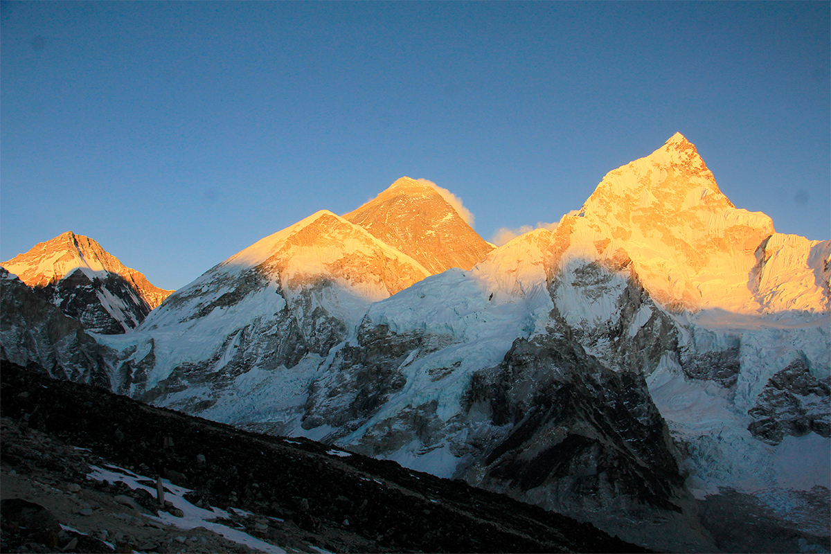 Yellow light of sun at the horizons of white snowy mountains