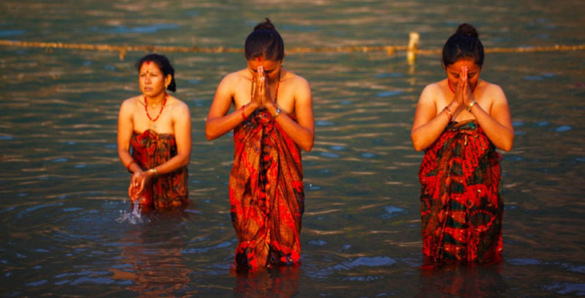 woman holding fire on hand in a river performing some ritual