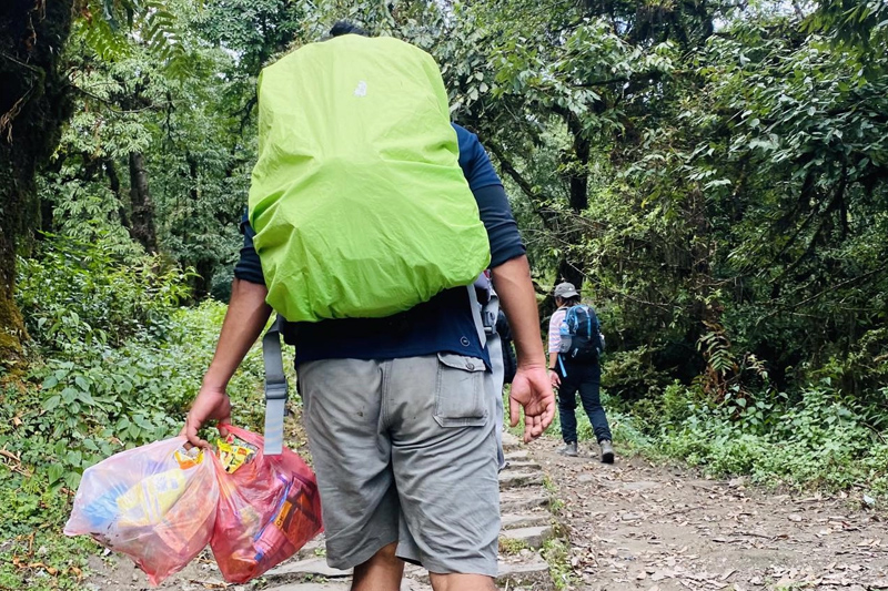 A traveler carrying bags of trash along with him returning from the trek