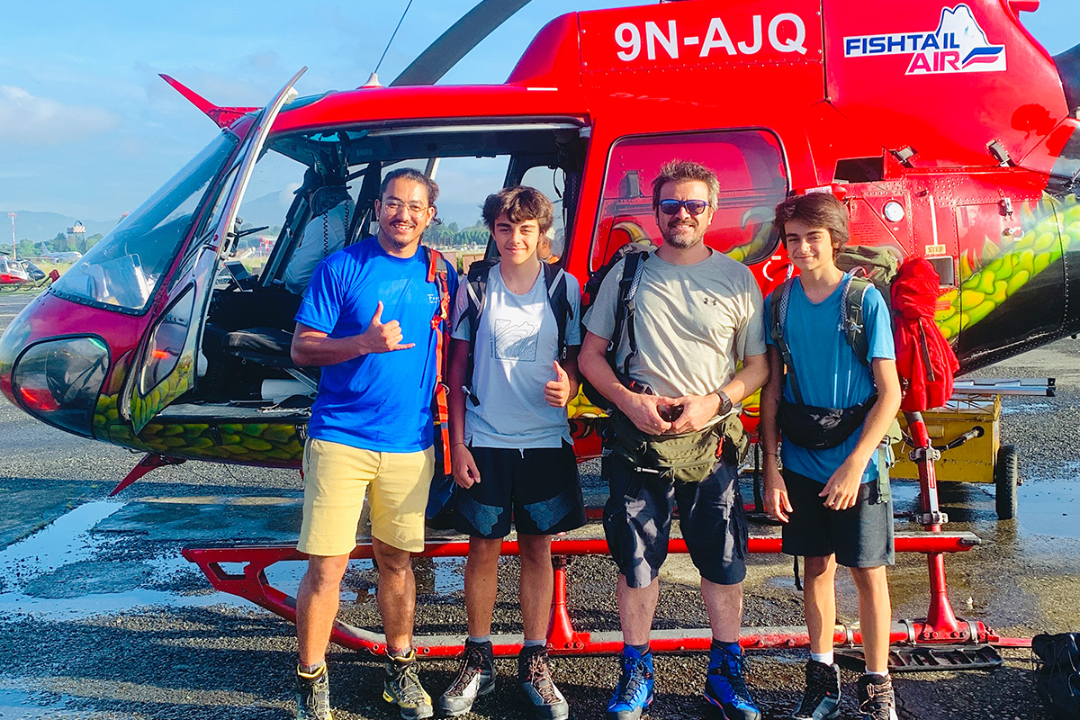 four men standing in-front of a red color helicopter